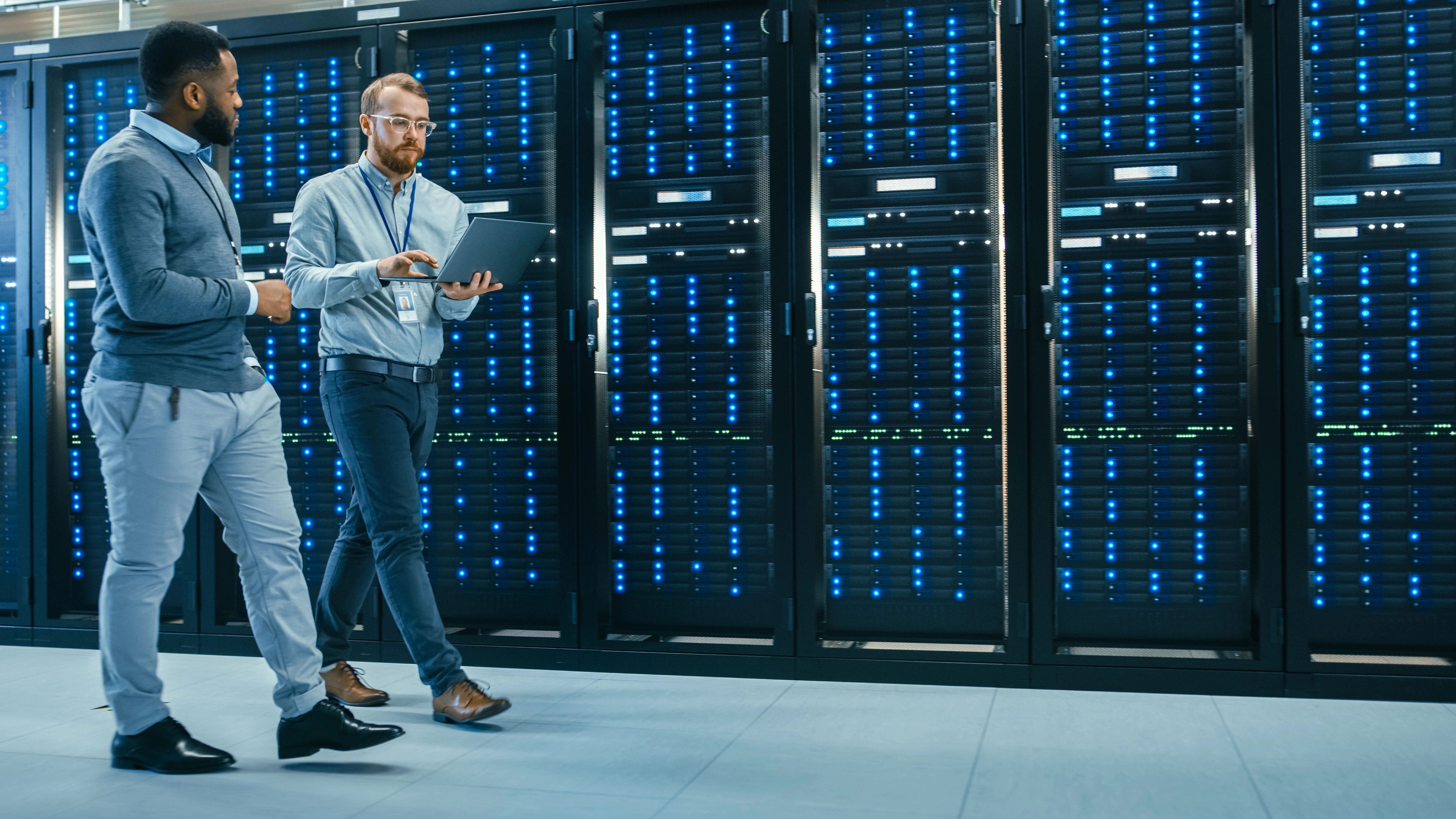 Two technicians walking next to a long row of racks containing servers